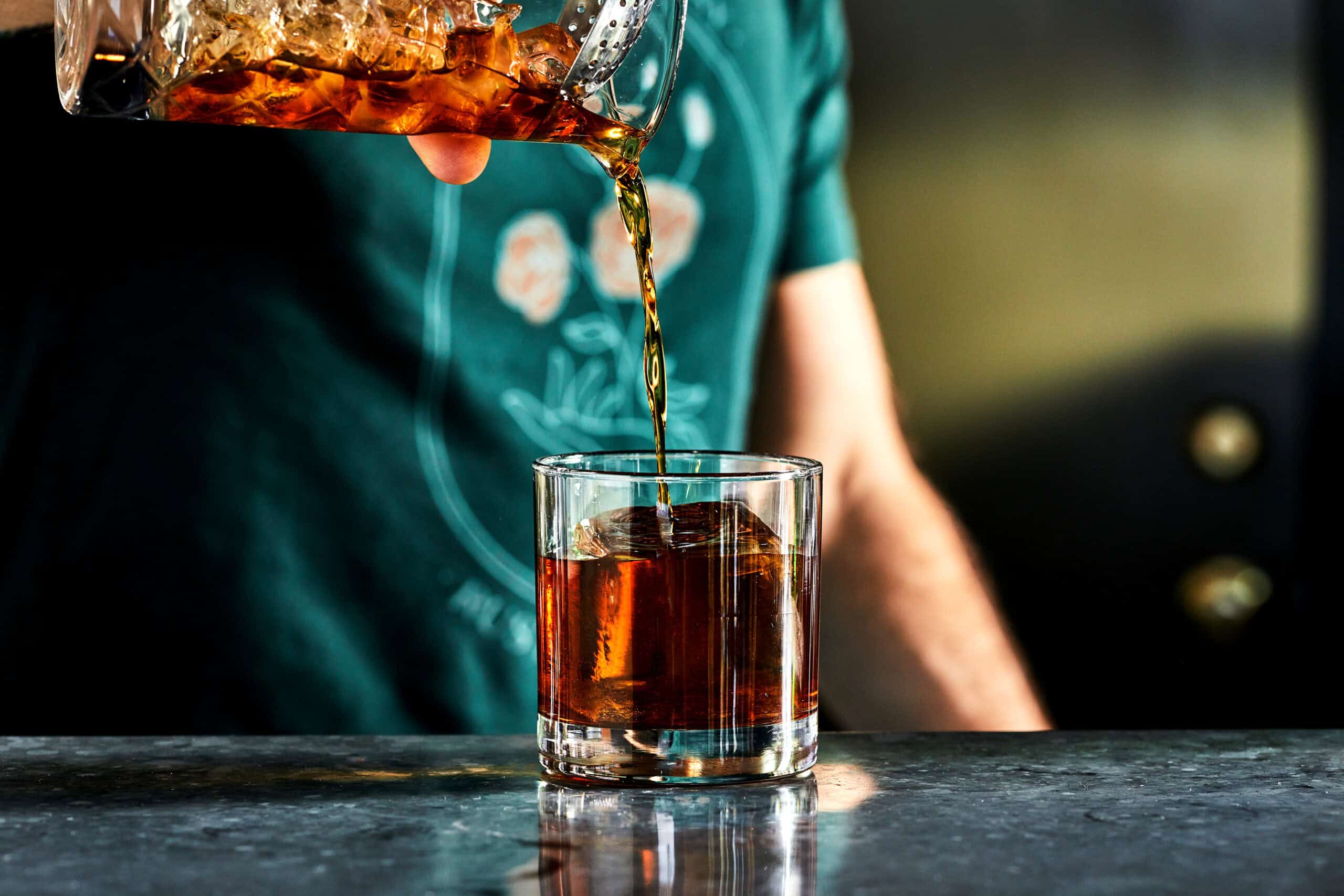 pouring a negroni cocktail into a rocks glass